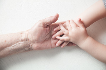Elderly woman and a kid hands together.