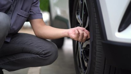 man filling air in the tires of his car (inflating tire)