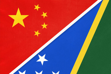 China or PRC vs Solomon Islands national flag from textile. Relationship between Asian and Oceania countries.