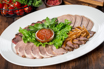 Sliced meat, several types of meat on a white plate.