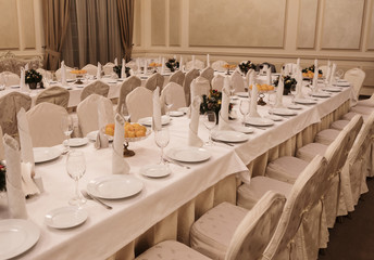 Festive table setting background. Serving a large festive restaurant table in anticipation of guests in a soft dim light.