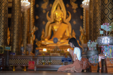 Woman traveller pay gentle respect to the buddha statue in the temple, praying respect for a better...