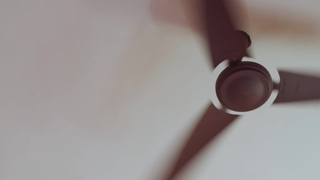 Low angle view of ceiling fan rotating with high speed indoors on white background. Electrical ventilator working circulating inside room copy space. Cooling equipment for hot season
