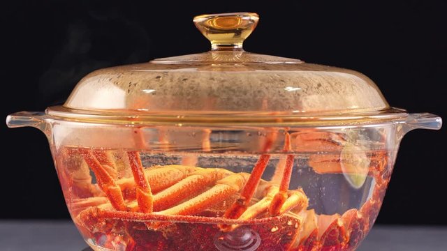 Time-lapse shot of boiling cooking raw fresh Cape rock lobster, West Coast rock lobster, Jasus lalandii in a glass pot, close up, 4K UHD footage video.