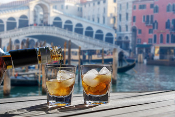 Drink for two in front of the Rialto bridge in Venice - Romantic holiday for couples. Two glasses of liqueur with ice on a sunny morning.