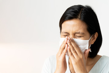 Woman sneezing under face mask covering mouth and nose while coughing.  Suspect people have to make 14-day Self-Quarantine. Corona Virus or COVID-19 concept.