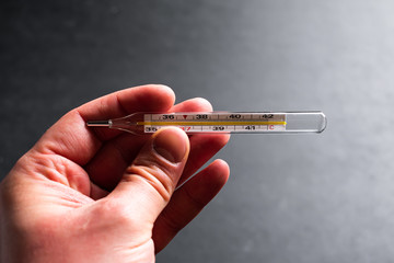 Male hands holding a thermometer with high temperature