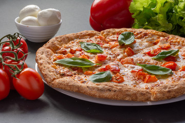 Pizza Margarita on a black background with tomatoes and mozzarella. Still-life.