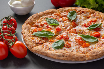 Pizza Margarita on a black background with tomatoes and mozzarella. Still-life.