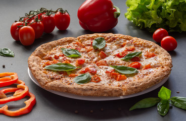 Pizza Margarita on a black background with tomatoes and mozzarella. Still-life.
