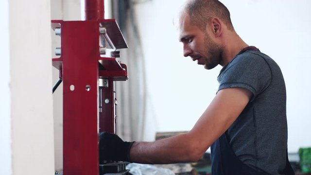 Man wears uniform and black gloves. Worker is at workplace. Man is mechanic.
