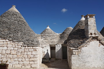 Fototapeta na wymiar Street detail of white round houses with specific architecture and stone roof from unesco world heritage Trulli of Alberobello in Italy