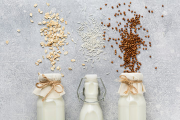 Vegetarian dietary milk from cereal rice, buckwheat and oats, three types of home-made on a gray concrete trend background.