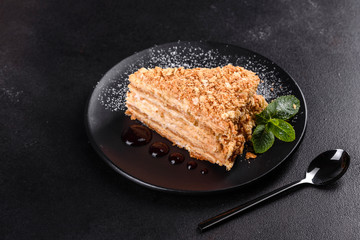 Fresh delicious cake napoleon with cream on a dark background