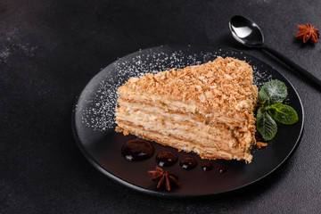 Fresh delicious cake napoleon with cream on a dark background