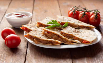 Mexican quesadilla with chicken, cheese, tomatoes and pepper on the table.