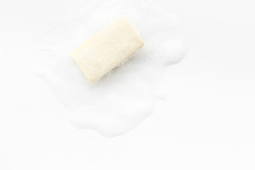 Soap bar with foam on white background top-down copy space