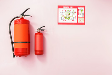 Fire extinguishers and evacuation plan on color background