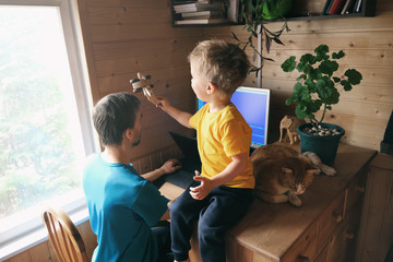 father freelancer try work from home, son child with cat sits and plays near, lifestyle workspace workplace