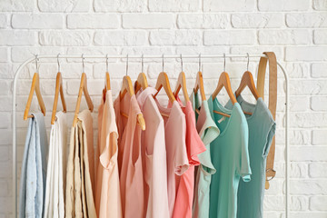 Rack with hanging clothes near brick wall