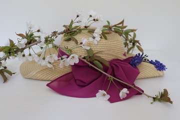  scented summer flowers in blossom placed on a summer straw hat on a plain backgroung
