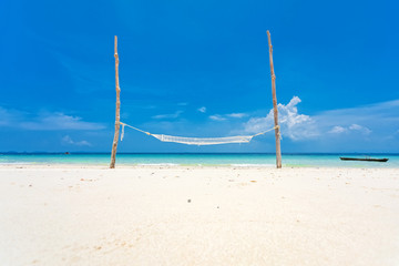 Fototapeta na wymiar Wooden hammock on a white sand beach. And blue sky.