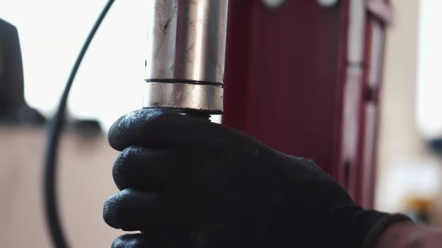 Person wears black gloves. Construction is red. Worker is in garage.