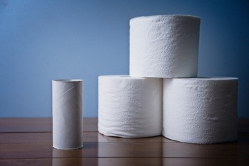 Empty toilet paper roll next to three full rolls on Wooden Bathroom counter. Essential toiletries and basic hygiene necessity. Washroom products stockpiled for sickness Soft TP 
