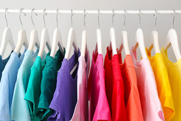 Rack with hanging clothes on grey background, closeup