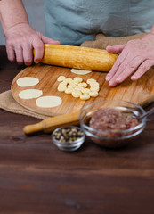 Chef's hands rolling small pieces of dough into a wide disk