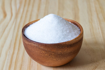 White sand sugar in wooden bowl on wooden table background..