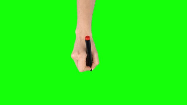Female hand with red marker is writing on green screen background. Close up