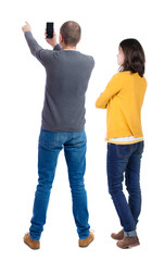 Fototapeta premium Back view of couple in sweater with mobile phone.