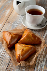 Traditional russian stuffed pierogi bake with golden crust, served on wooden table with a cup of tea