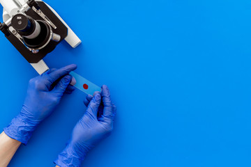 Microscope medical reserch. Hand holds blood sample. Blue table top-down copy space