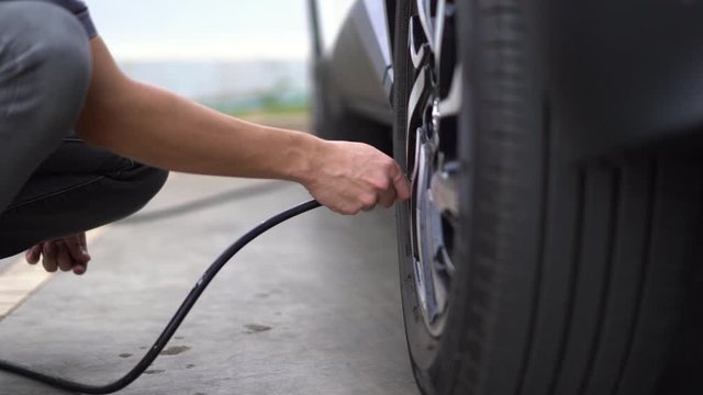 man filling air in the tires of his car (inflating tire)