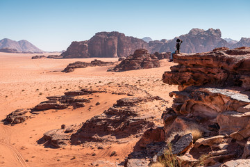 A woman traveller sitting on rock and looking to landscape of Wadi Rum desert in Jordan, Arab