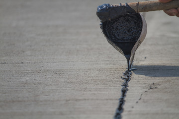 Worker sealing asphaltic joint for construction joint on concrete pavement, filling expansion joint concrete pavement.