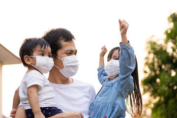 Asian father holding his daughter and son and all of people wear a mask to protect the corona virus and pm 2.5 dust in air, concept of people living in the crisis of covid-19 and air pollution problem