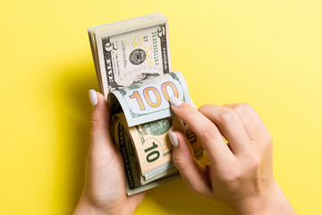 Top view of female hands counting money. One hundred and other dollar banknotes on colorful background. Business concept