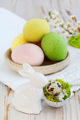 Easter table decoration with colorful eggs and ceramic  rabit figurine.
