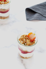 Small jars of granola with yogurt-strawberry jam and fresh strawberries.