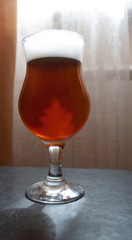 dark beer in a glass is on the table