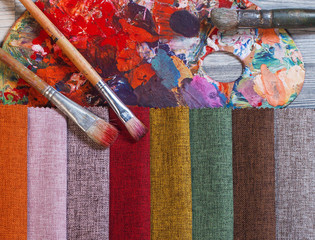 Colorfull textile lies on a colorfull palette of the artist. Colored brushes and fabrics.
