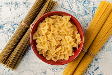 dry pasta in a red mask and bunches of spaghetti on a white and blue textured background