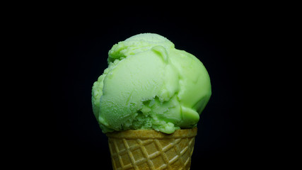 Scoop lime flavoured sherbet ice cream in waffle cone on black background, Closeup Front view Food concept.