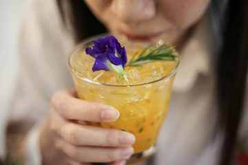 Close up a  beautiful woman with Passion fruit juice iced in a glass on wooden table in cafe.