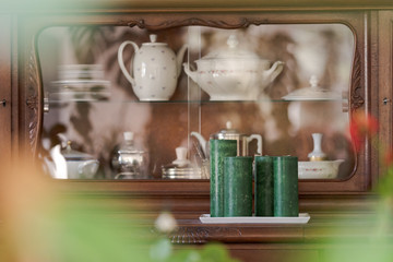 Front of wooden old sideboard filled with grandmother´s teapots and plates seen through blurred...