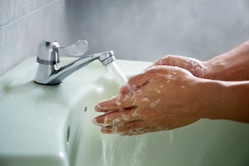 Fototapeta premium Washing of hands with soap under the crane with water
