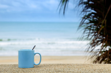 blue cup on the beach with blue sea and sky